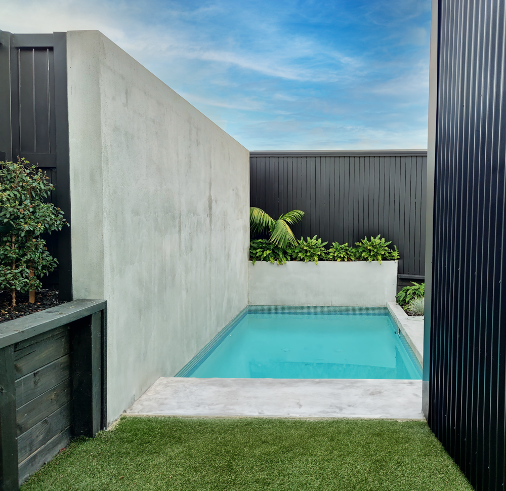 Small pool in concrete yard corner with planter boxes